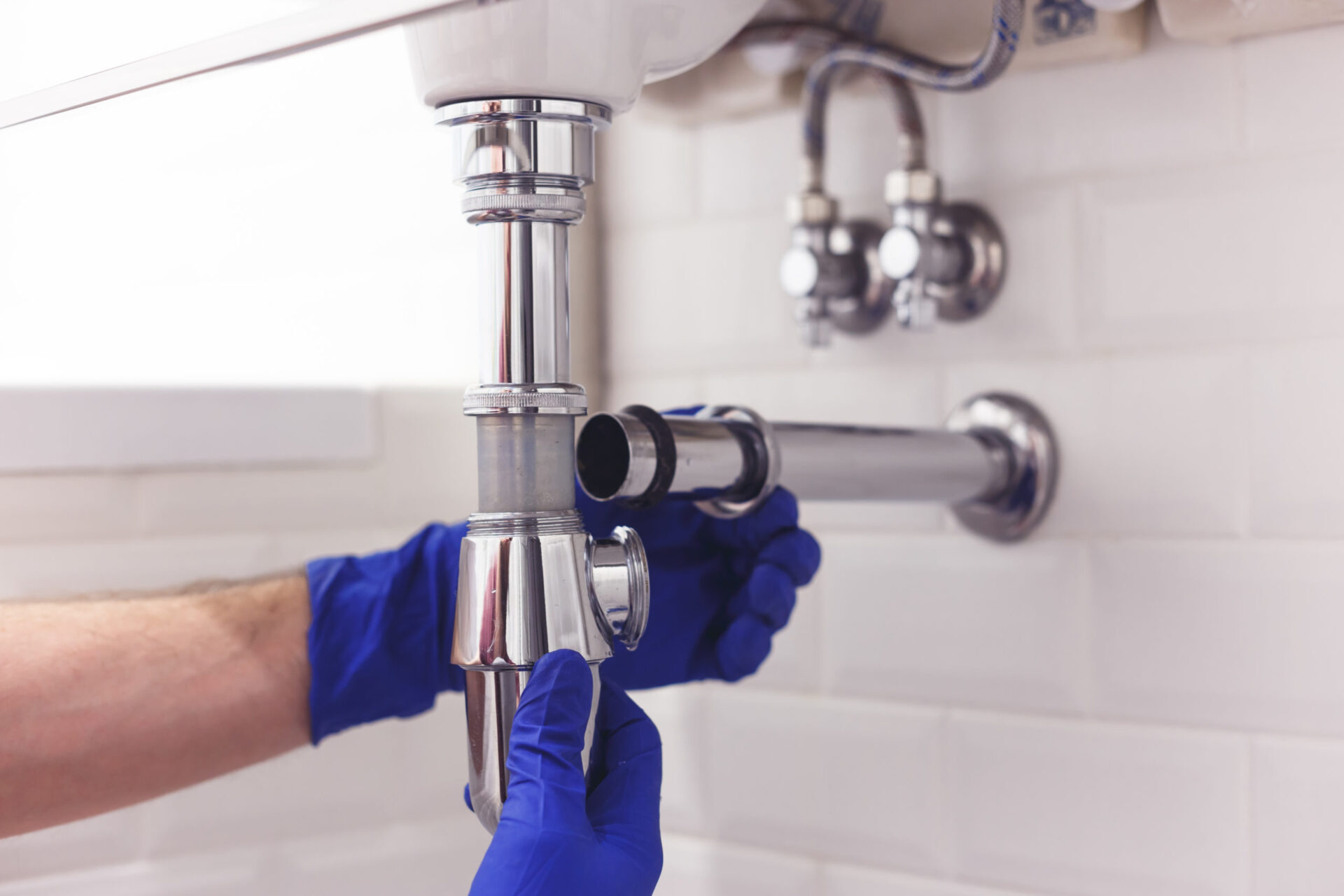 plumber working on drain cleaning under a bathroom sink, Blanco TX plumbing service pros